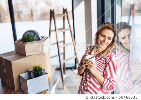 A young woman moving in new home, drinking coffee. 50468538