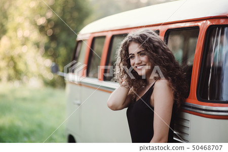 A young girl on a roadtrip through countryside, standing by a minivan. 50468707