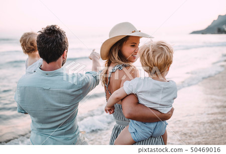 A family with two toddler children walking on beach on summer holiday at sunset. A family with two toddler children walking on beach on summer holiday at sunset. 50469016