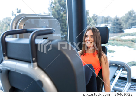 Slim smiling woman using a leg press machine and Slim smiling woman using a leg press machine and 50469722