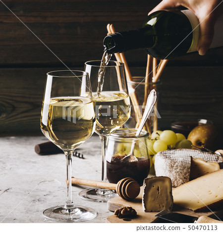 White wine pouring into glasses with charcuterie assortment White wine pouring into glasses with charcuterie assortment 50470113