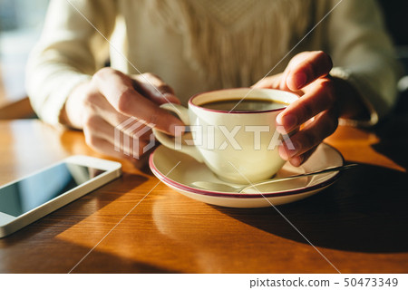 Woman holding in hands cup of coffee on wooden background Woman holding in hands cup of coffee on wooden background 50473349
