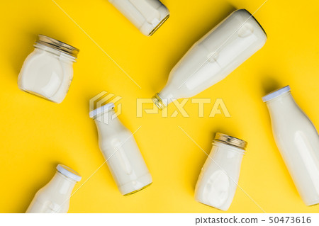 Various bottles of milk on yellow background Various bottles of milk on yellow background 50473616