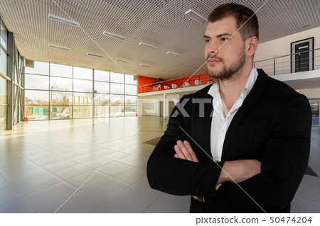 Beautiful serious business man on empty dealer center background 50474204