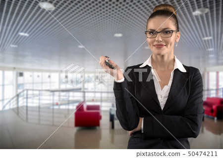 Beautiful serious business woman with glasses on empty dealer center background Beautiful serious business woman with glasses on empty dealer center background 50474211
