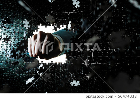 Figure breaking a puzzle face with a fist punch 50474338