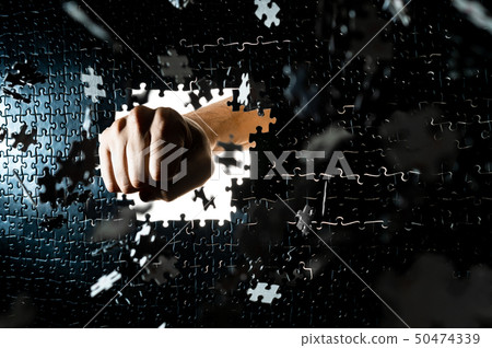Figure breaking a puzzle face with a fist punch 50474339