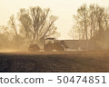 Sowing time. Blue tractor rides through the agricultural field in the sunlight. 50474851