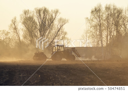 Sowing time. Blue tractor rides through the agricultural field in the sunlight. Sowing time. Blue tractor rides through the agricultural field in the sunlight. 50474851