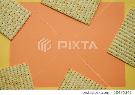 Five pieces of Matzo on the coral and yellow background. Empty space for text. Trendy concept. 50475341