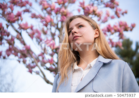 Portrait of Beautiful blonde girl posing with blooming Magnolia tree branches with pink flowers on Portrait of Beautiful blonde girl posing with blooming Magnolia tree branches with pink flowers on 50475937