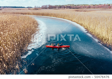 two athletic man floats on a red boat in river 50476476