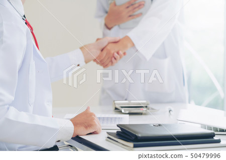 Doctor at hospital shakes hand with another doctor Doctor at hospital shakes hand with another doctor 50479996