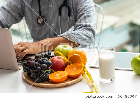 Senior male nutritionist doctor working at desk. 50480007