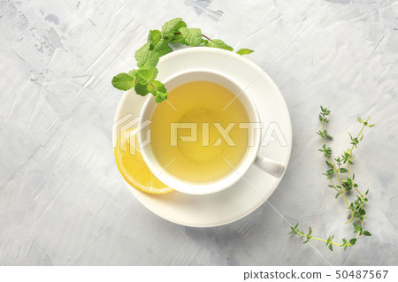 A cup of green tea with lemon, shot from the top with herbs and a place for text 50487567