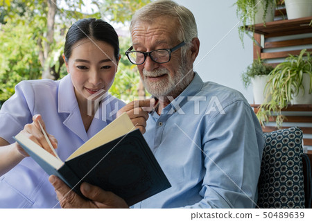 senior man happiness with smiling nurse, read book senior man happiness with smiling nurse, read book 50489639