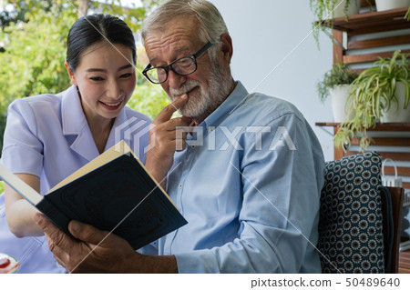 senior man happiness with smiling nurse, read book senior man happiness with smiling nurse, read book 50489640
