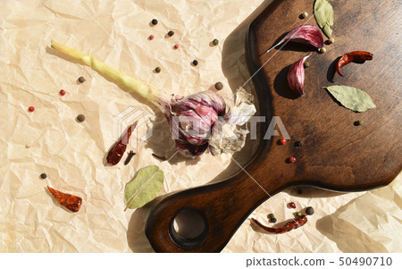 Garlic and various spices for dressing dinner dishes on a wooden board. Dark wood, bay leaf, chili Garlic and various spices for dressing dinner dishes on a wooden board. Dark wood, bay leaf, chili 50490710