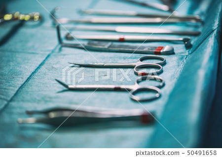 Set of sterile instruments laid out on the table for an operation on a blue cloth Set of sterile instruments laid out on the table for an operation on a blue cloth 50491658