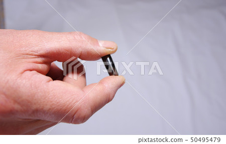 Elderly hand holding concentrated garlic extract in a capsule 50495479