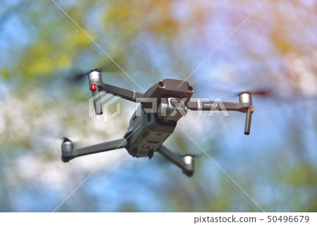 Flying drone with camera hovering inside a forrest 50496679