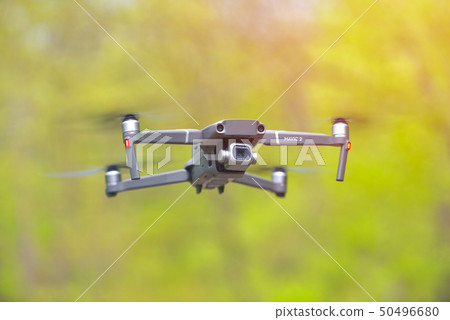 Flying drone with camera hovering inside a forrest 50496680