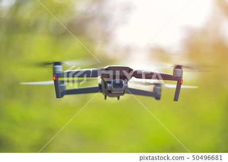 Flying drone with camera hovering inside a forrest 50496681