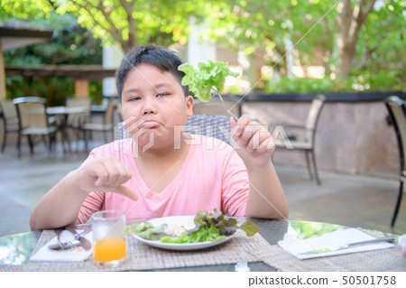 Boy with expression of disgust against vegetables Boy with expression of disgust against vegetables 50501758