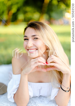 Young smiling caucasian woman lying in park on plaid. Young smiling caucasian woman lying in park on plaid. 50503530