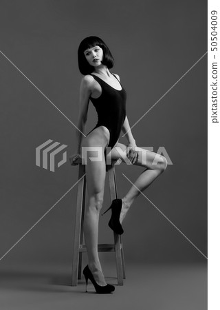 Beautiful model posing near high chair in studio. Beautiful model posing near high chair in studio. 50504009