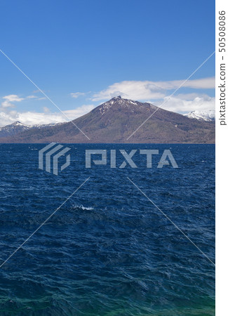 Photographing the landscape of the remaining snow Eniwadake from the lakeside of Lake Shikotsu, Chitose, Japan 50508086