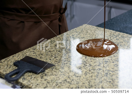 Chocolatier pours liquid chocolate  50509714