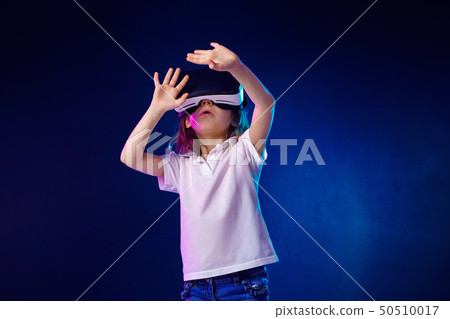 Girl 7 y.o. experiencing VR headset game on colorful background. Child using a gaming gadget for Girl 7 y.o. experiencing VR headset game on colorful background. Child using a gaming gadget for 50510017
