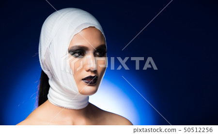 Asian Tan Skin Woman with Bandage around head after brain beauty plastic surgery Operation and Nose reshaping treatment rhinoplasty. Studio Lighting gradient Blue Background, Concept Propaganda Asian Tan Skin Woman with Bandage around head after brain beauty plastic surgery Operation and Nose reshaping treatment rhinoplasty. Studio Lighting gradient Blue Background, Concept Propaganda 50512256