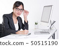 Businesswoman working at desk in busy office 50515190