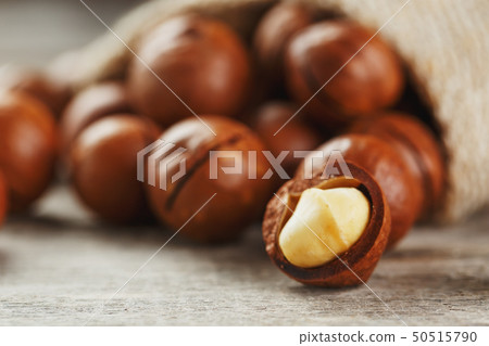 Macadamia nuts spilled out of the bag on a wooden 50515790