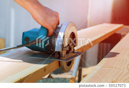 Cutting wood beam using an electrical chainsaw 50527071