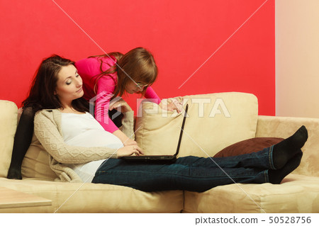 Pregnant woman and daughter sitting with laptop Pregnant woman and daughter sitting with laptop 50528756