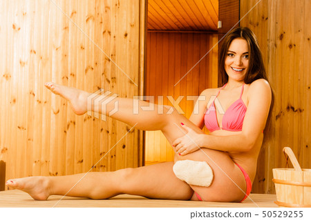 Happy woman in sauna with exfoliating glove. 50529255