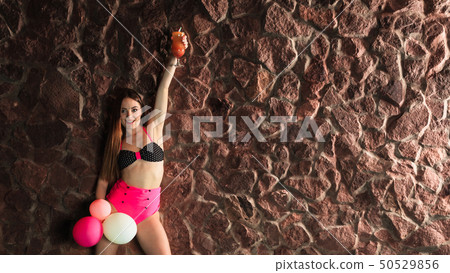 Woman with coctail and balloons on pool. 50529856