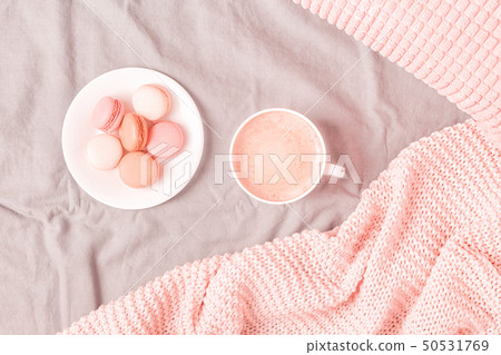 Bed with pink knitted plaid, coffee and macaroons. 50531769