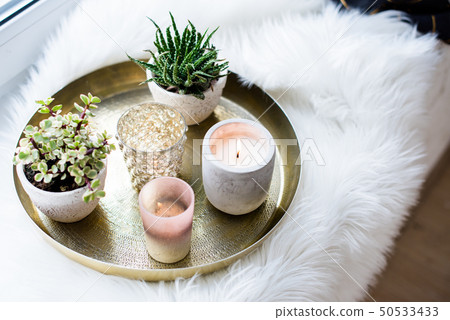 Cozy real home decoration, burning candles on golden tray with pillow on white faux fur on Cozy real home decoration, burning candles on golden tray with pillow on white faux fur on 50533433