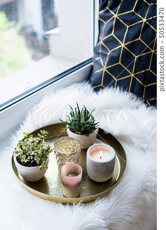 Cozy real home decoration, burning candles on golden tray with pillow on white faux fur on Cozy real home decoration, burning candles on golden tray with pillow on white faux fur on 50533470