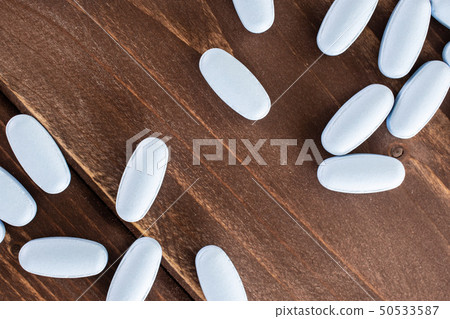 Blue medical pills on brown wood Blue medical pills on brown wood 50533587