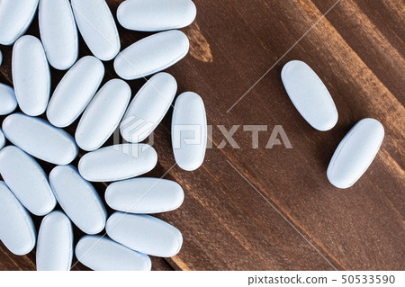 Blue medical pills on brown wood 50533590