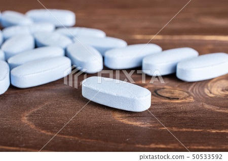 Blue medical pills on brown wood Blue medical pills on brown wood 50533592