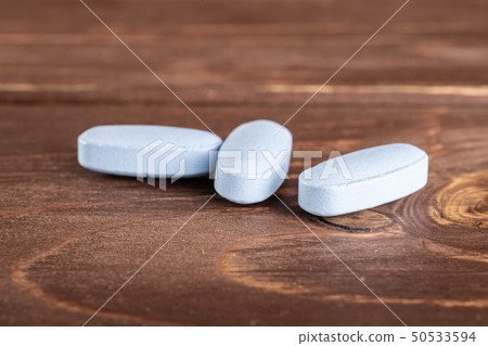 Blue medical pills on brown wood 50533594