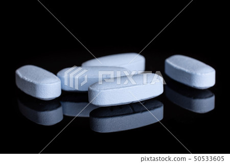 Blue medical pills isolated on black glass Blue medical pills isolated on black glass 50533605