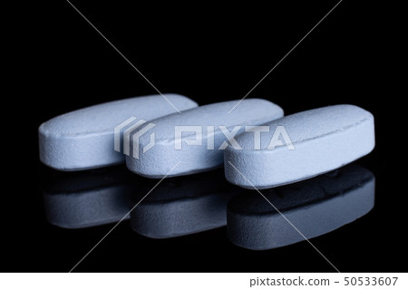 Blue medical pills isolated on black glass Blue medical pills isolated on black glass 50533607