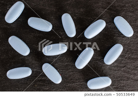 Blue medical pills on grey stone 50533649